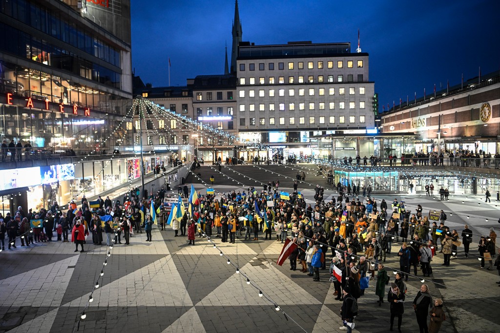 デモ隊は、スウェーデンのストックホルムでのデモ中にウクライナの旗と反戦の旗を掲げています。 