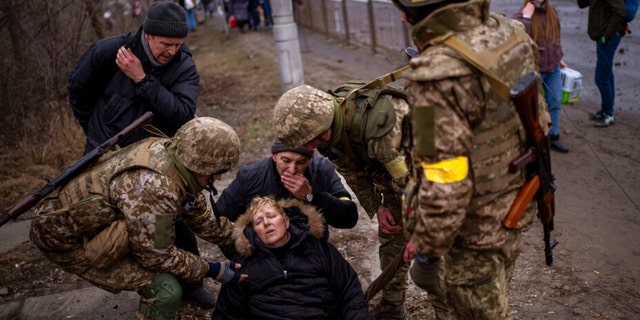 ウクライナの兵士は、2022年3月5日土曜日、ウクライナのキエフ郊外で都市から逃げている間にイルビン川を渡った後、半意識のある女性の世話をします。 