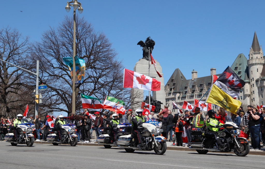 バイクの警官がデモを通過し、コンボイスタイルのデモコールの一部 "ローリング・サンダー" オンタリオ州オタワで、2022年4月30日土曜日。