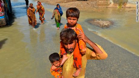 土曜日、パキスタン南西部のバロチスタン州ジャファラバードにある洪水で被害を受けた自宅から娘たちを運ぶ避難民の男性。 