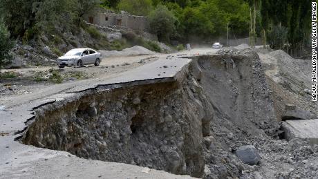 パキスタンのギルギット・バルティスタン地域で氷河湖が爆発した後、被害を受けたパキスタンのカラコルム高速道路の部分的に崩壊した区間を通過する車。