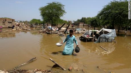 木曜日、パキスタンのシンド州のシカルプール地区にある浸水した自宅から、救助可能な持ち物を探す男性。