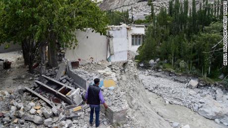 6月、パキスタン北部のハッサナーバード村で氷河湖の爆発により壊滅的な洪水が発生した後、破壊された自宅の隣に立つ地元住民。 