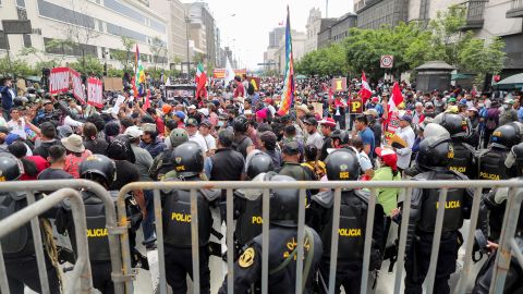 ペドロ・カスティージョ大統領が 12 月 7 日に議会を解散すると述べた後、人々がペルー議会の外に集まる中、警察官が見張りをしている。