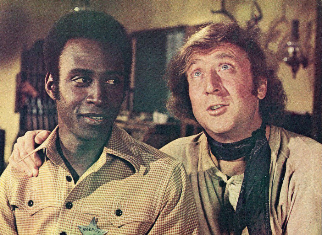 ジーン・ワイルダー (右) は映画の静止画でクリーボン・リトルの肩に腕を回している. "燃えるサドル、" メル・ブルックス監督、1974年。