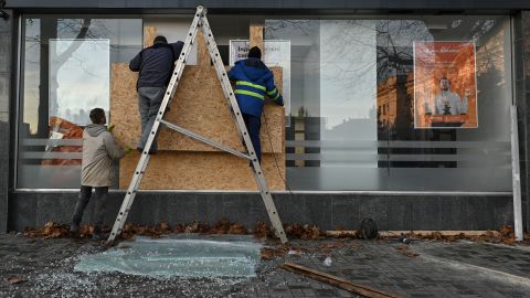 水曜日のヘルソン市でのロケット弾攻撃の後、男性はヘルソン州政府の建物の隣の銀行の窓に木の板を挿入します.