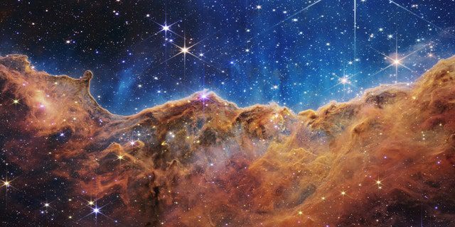 月明かりに照らされた夜の岩山のように見えるものは、実際には近くのりゅうこつ星雲の若い星形成領域 NGC 3324 の端です。  NASA のジェームズ ウェッブ宇宙望遠鏡に搭載された近赤外線カメラ (NIRCam) によって赤外線で撮影されたこの画像は、これまで不明瞭だった星の誕生領域を明らかにしています。
